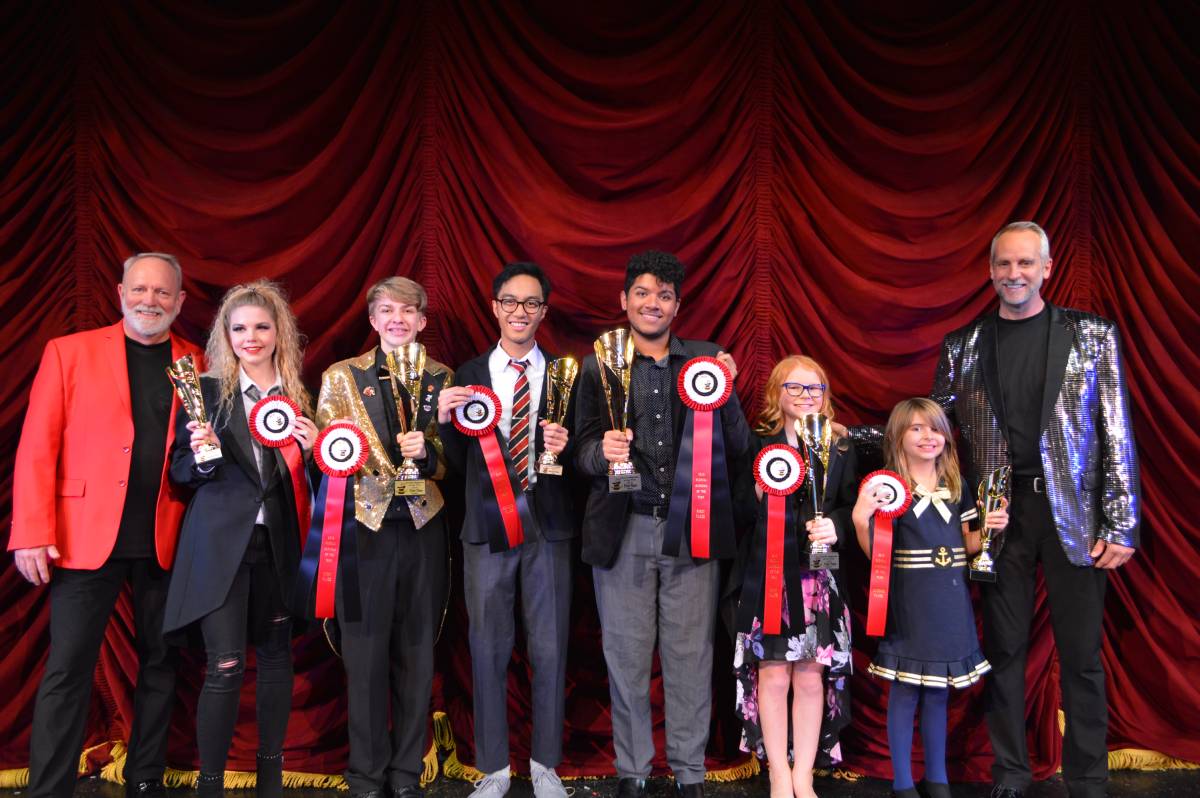 A group of people holding trophies on stage.