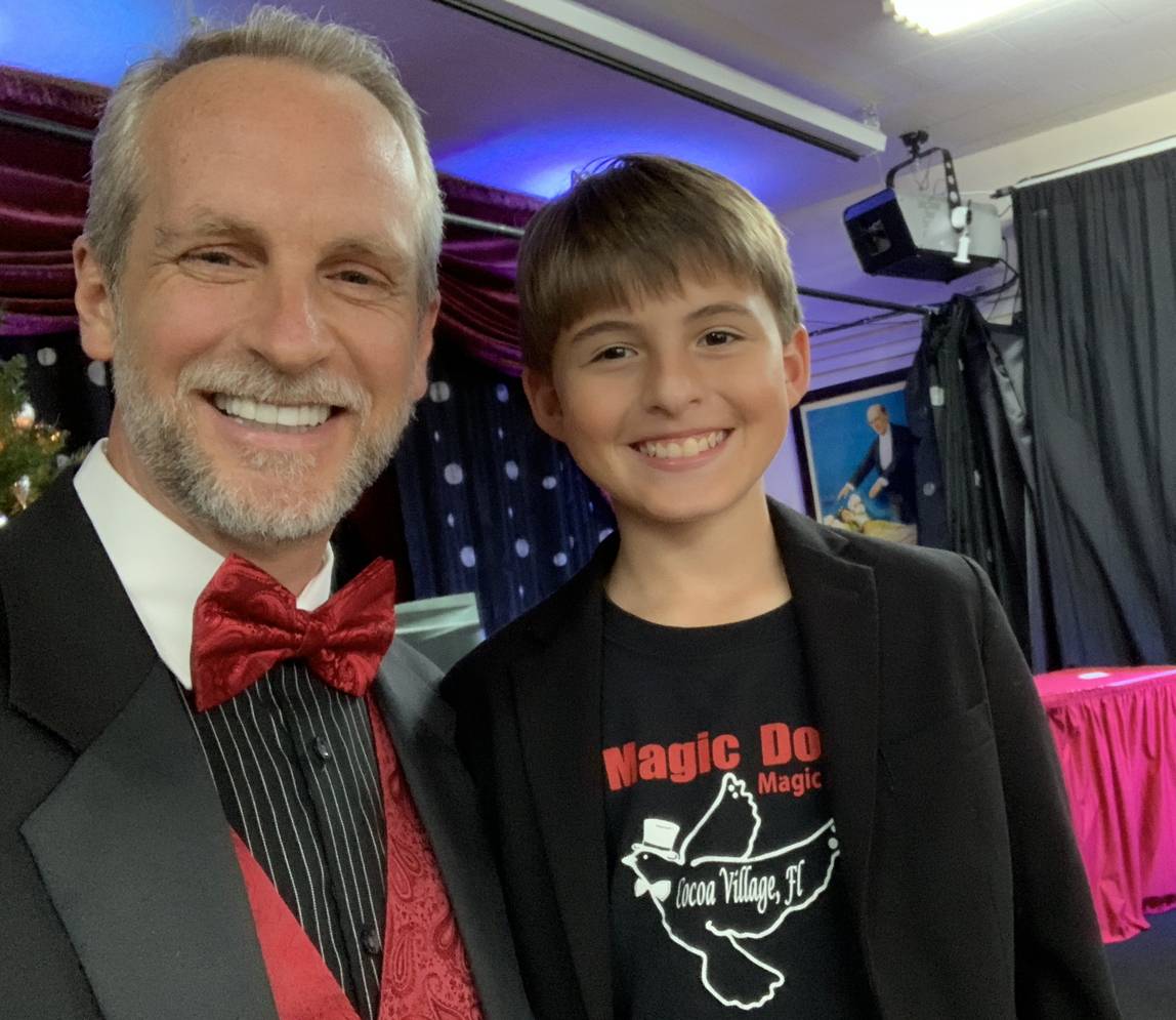 A boy smiling and taking a picture with the magician
