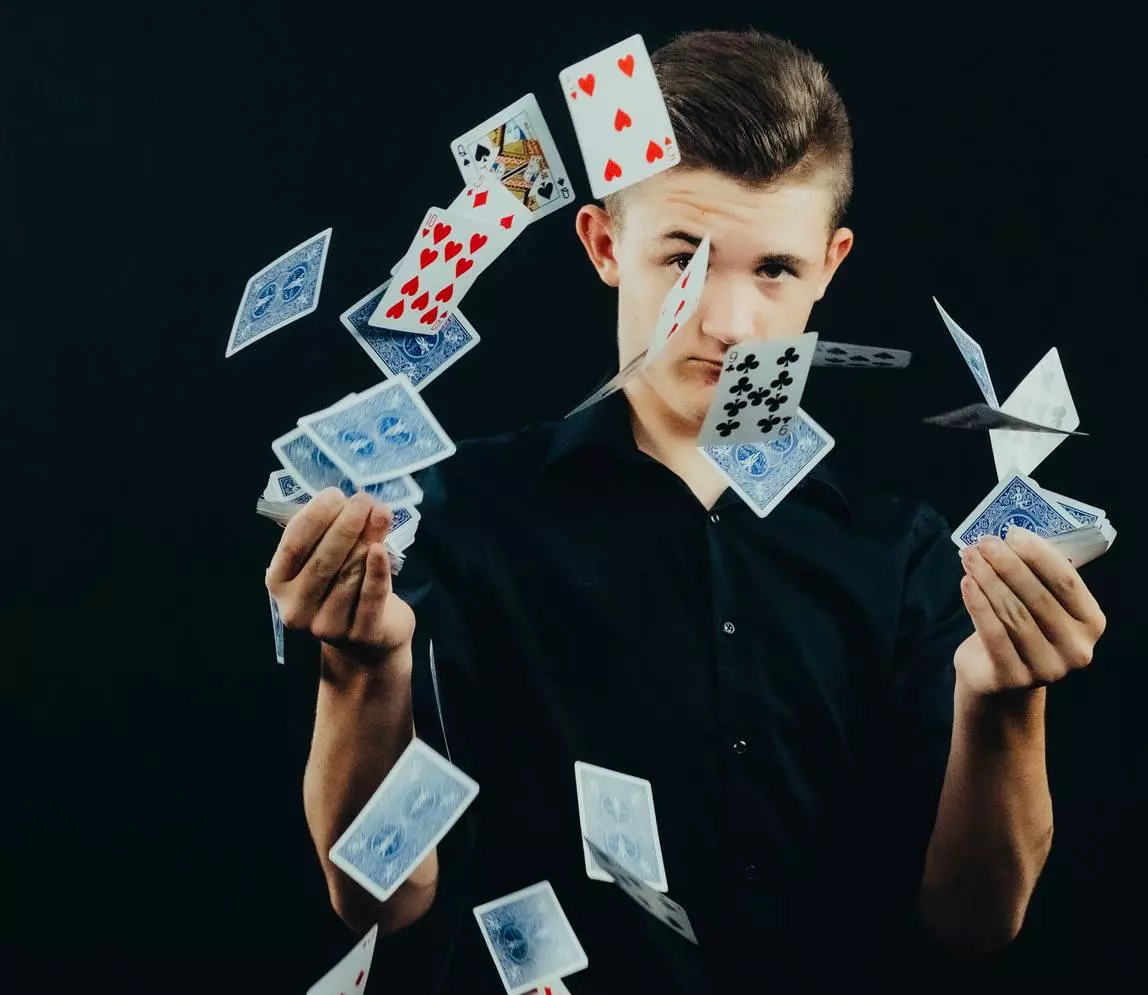 A boy throwing deck cards in the air