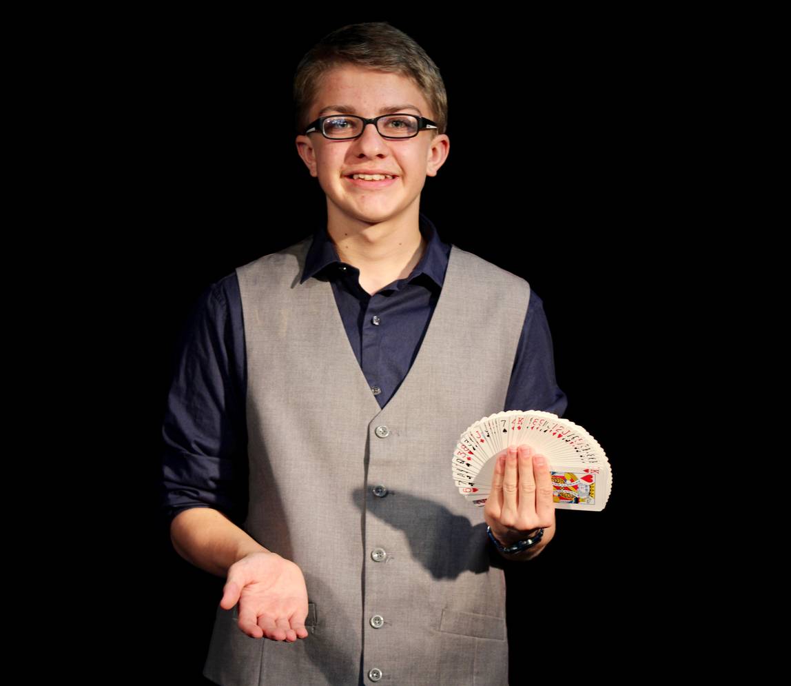 A boy holding a deck of cards and smiling