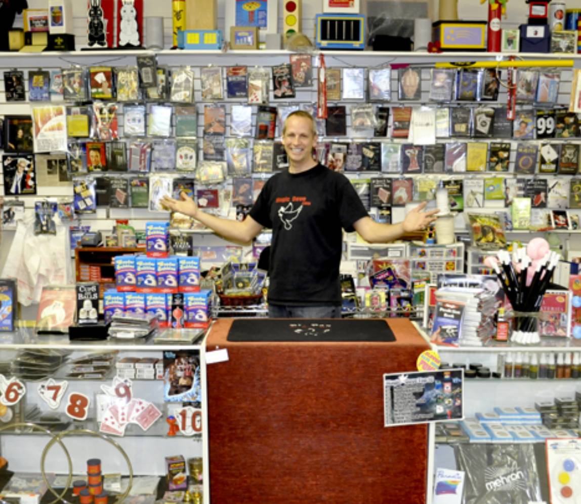 A magician standing and smiling at a magic store