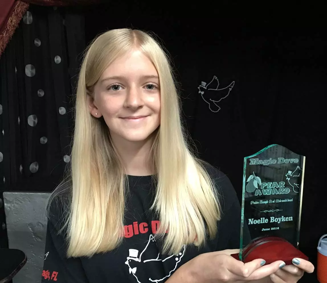 A girl with white hair holding a Pear Award