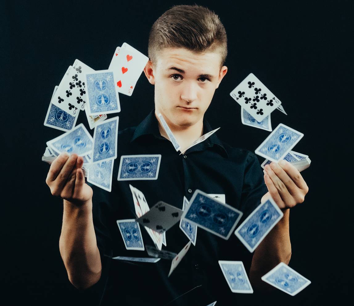 A boy looking serious and throwing a deck of card