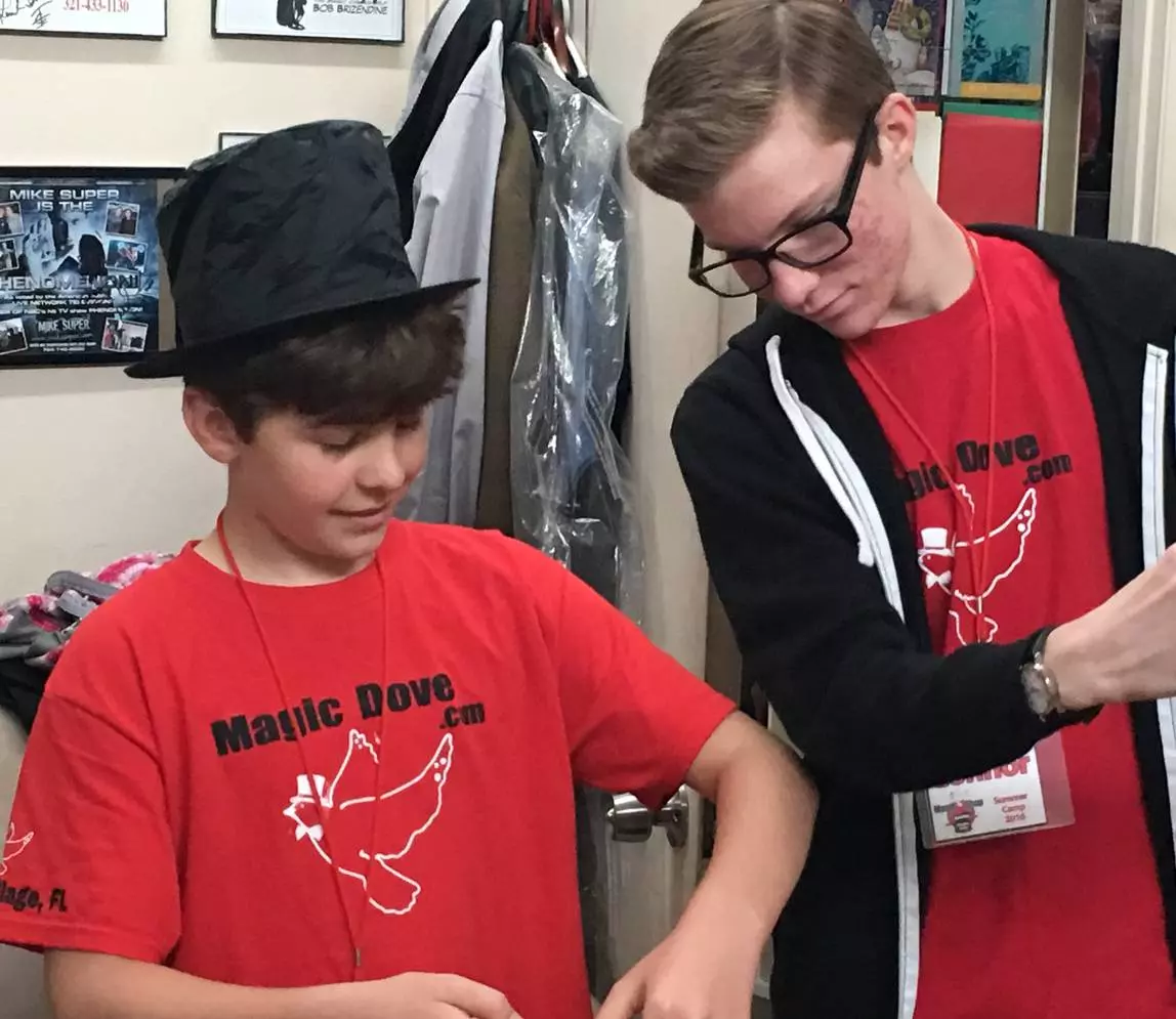 A boy wearing a red color shirt and a magician hat