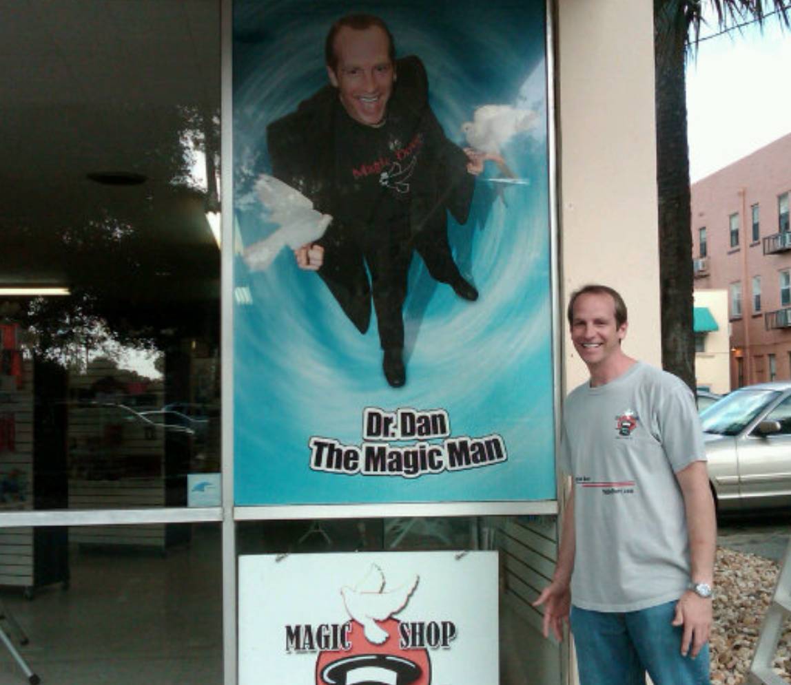 A man standing in front of a poster gr Dan the magic man