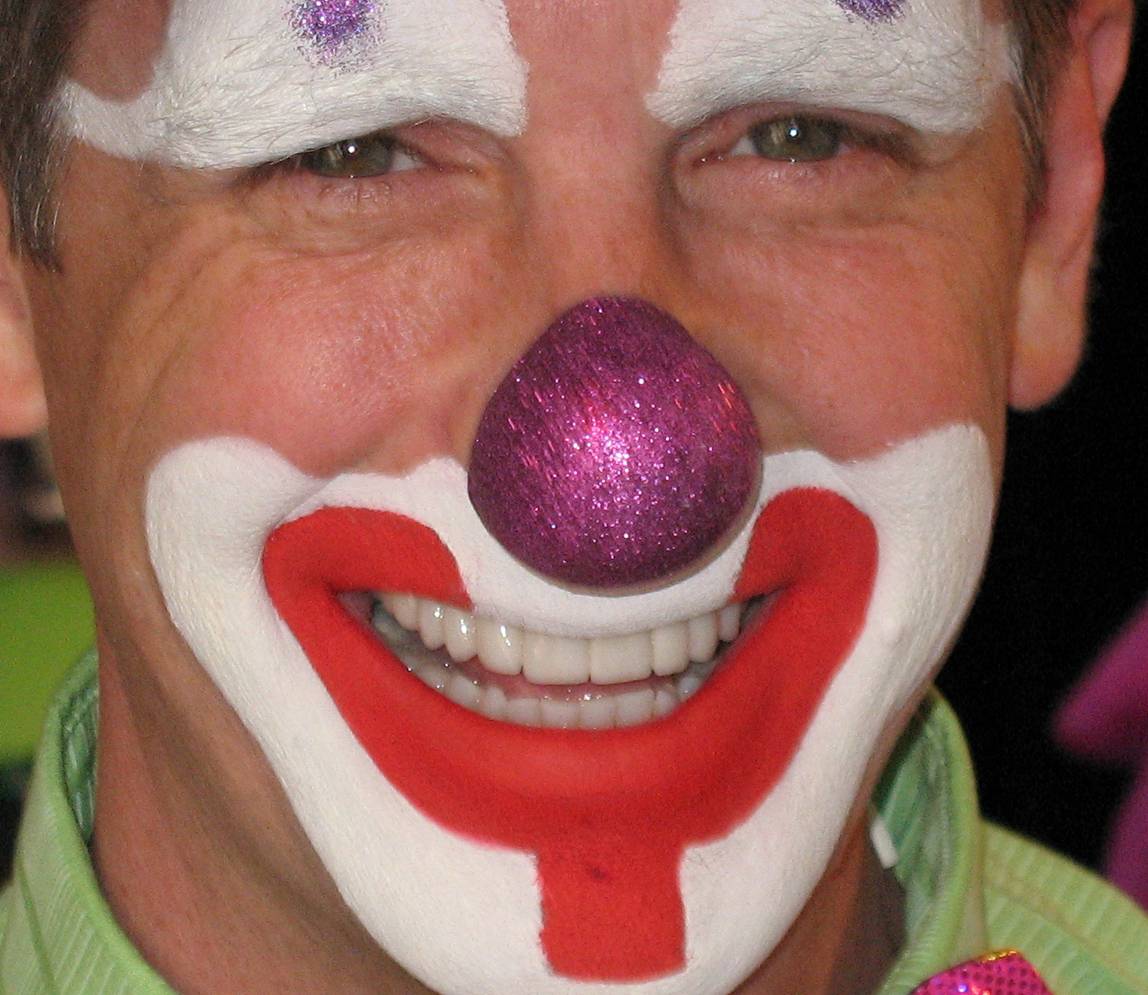 A man with clown face paint and smiling