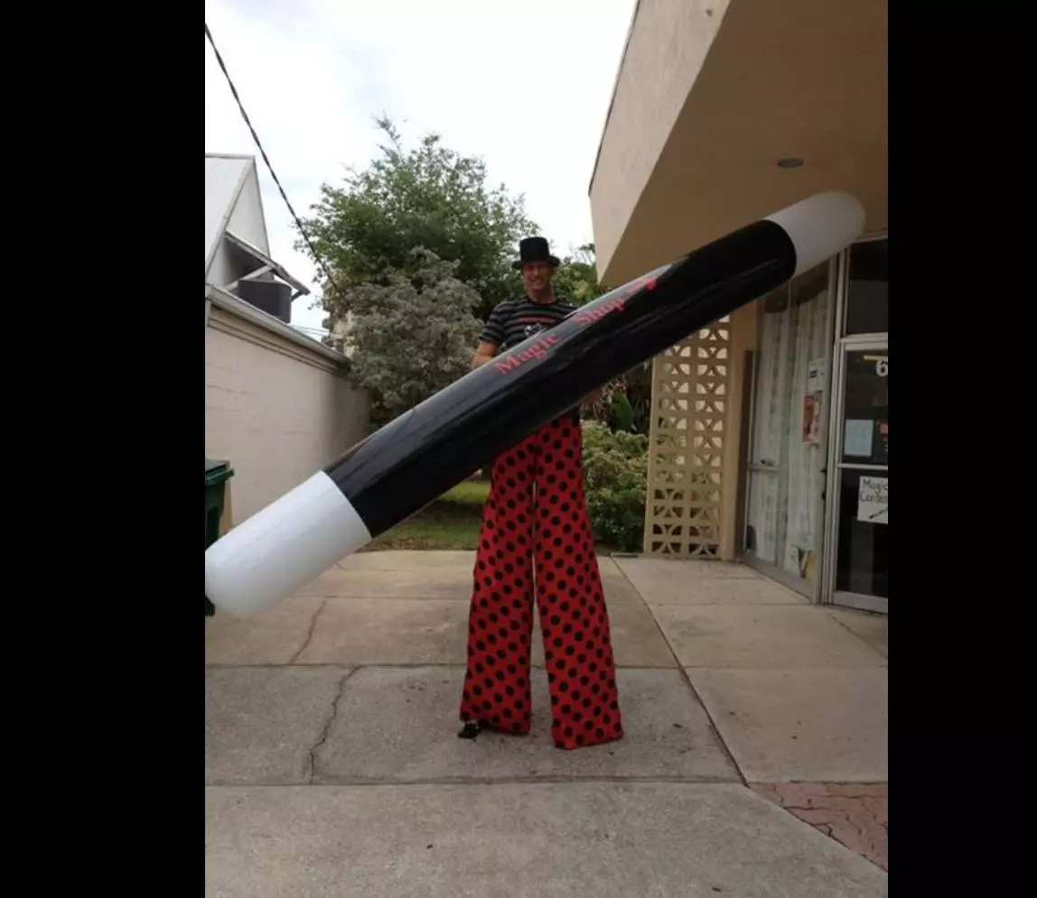 A man from circus holding a sponge with black in middle and white on botj ends