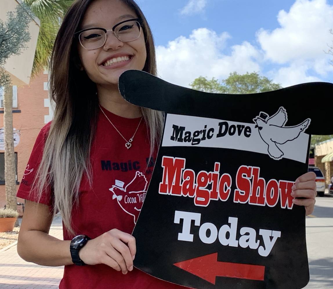 Magic Dove Magic Shop sign board carried by a woman