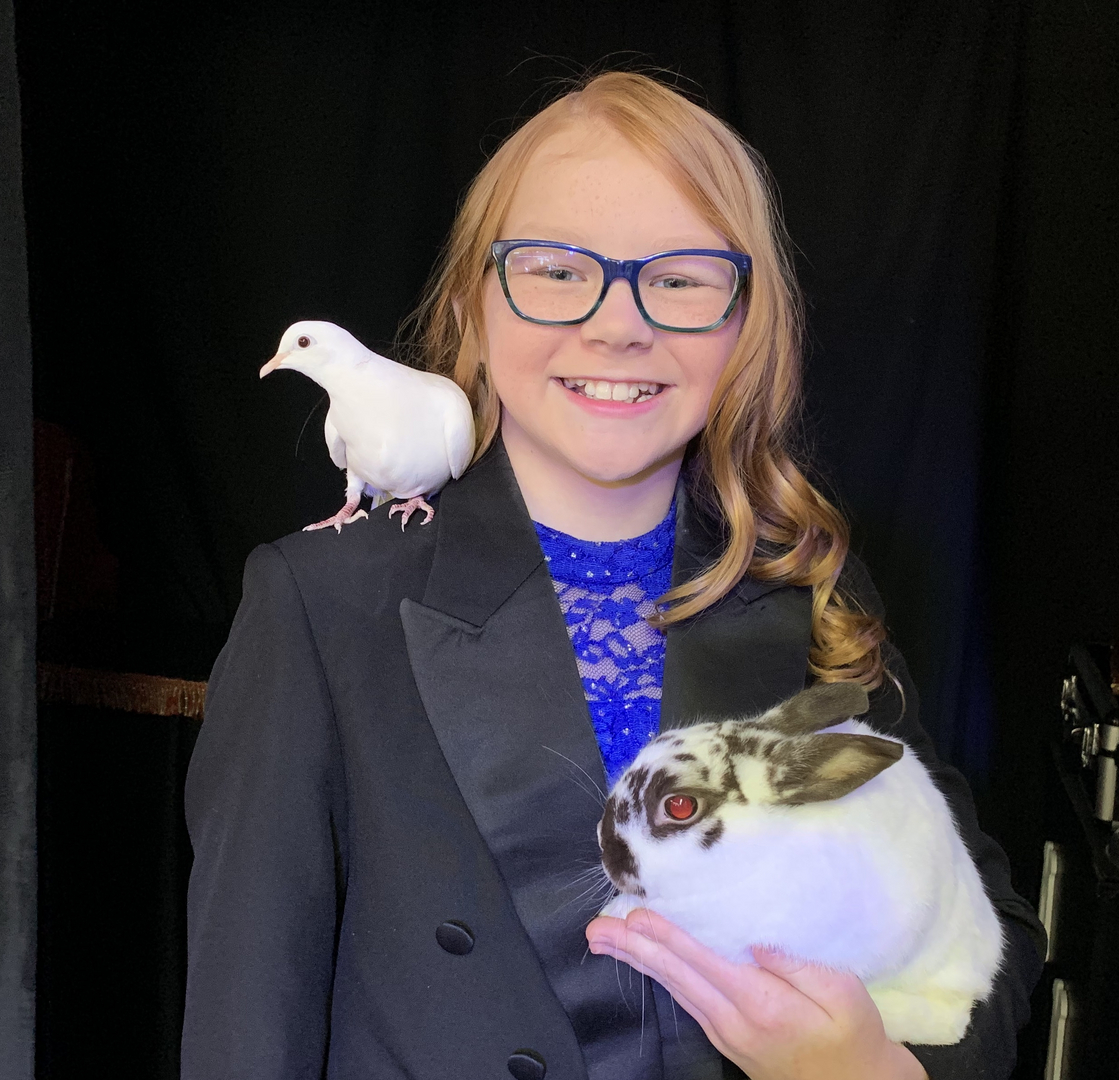 A girl holding a pigeon and a dove.