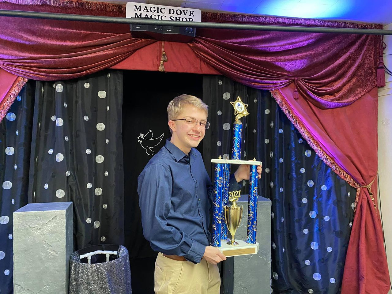 A young man holding a trophy in front of a curtain.