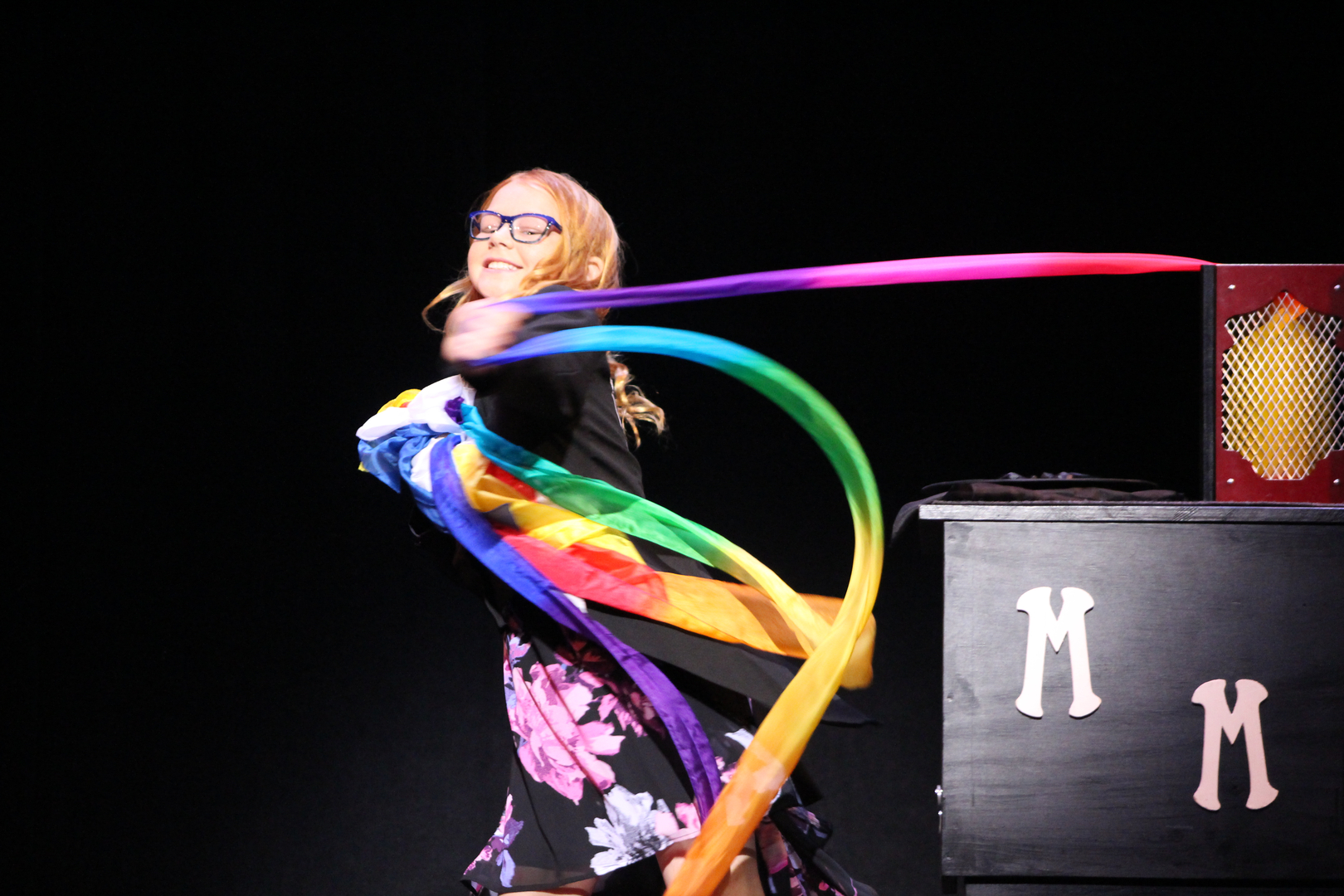A woman holding a colorful ribbon on stage.