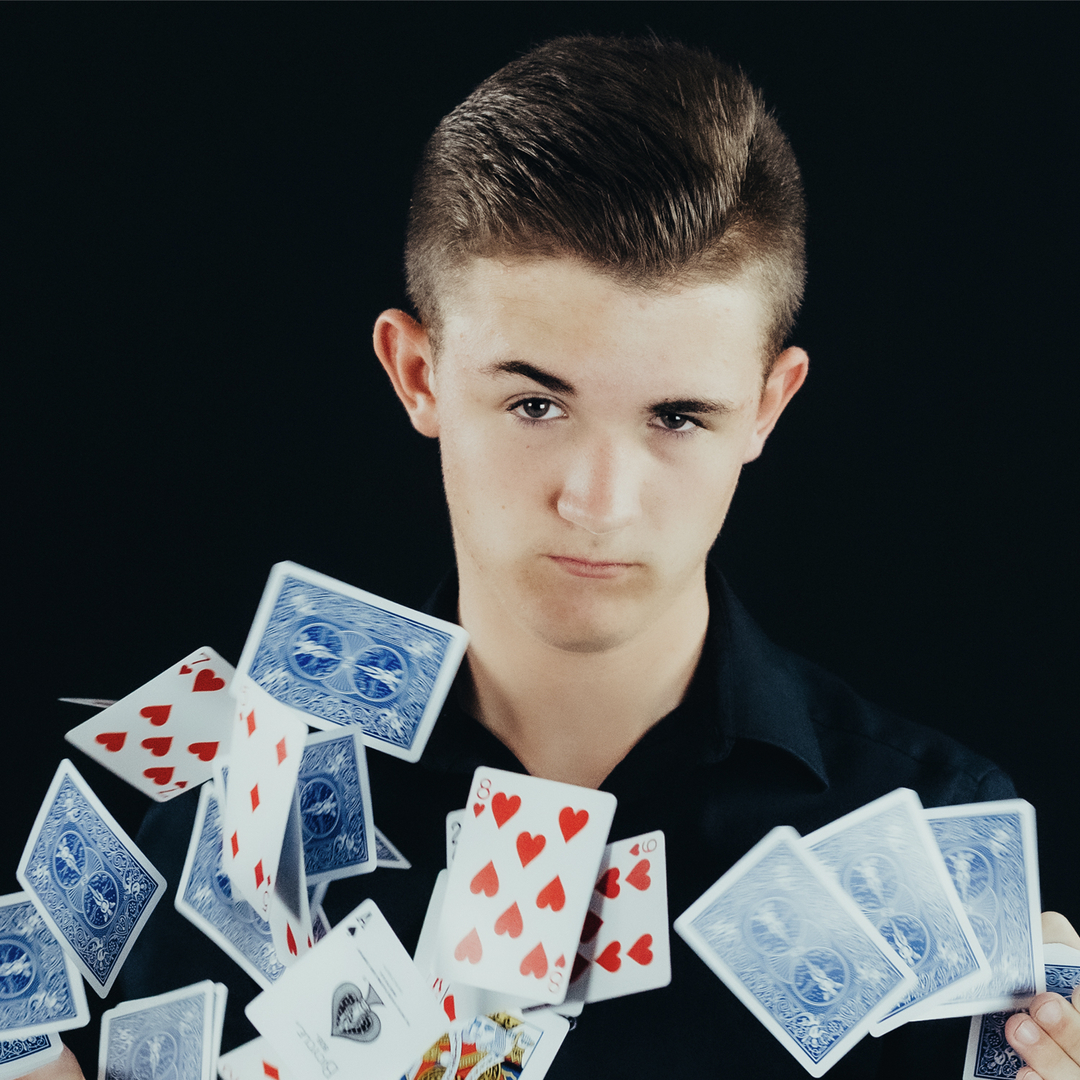 A young man holding a bunch of playing cards.