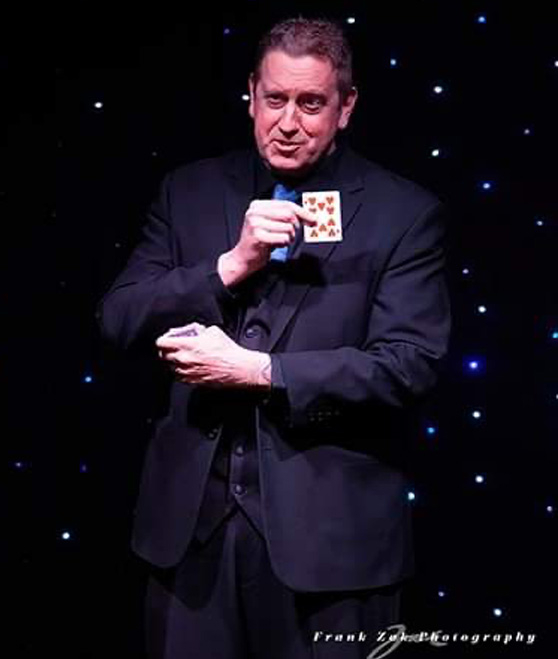 A man in a suit holding a card in his hand.