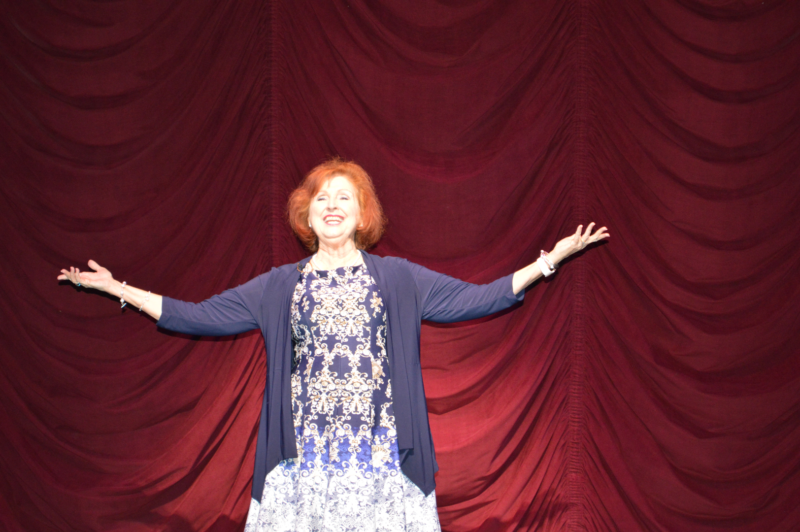 A woman standing on stage with her arms outstretched.