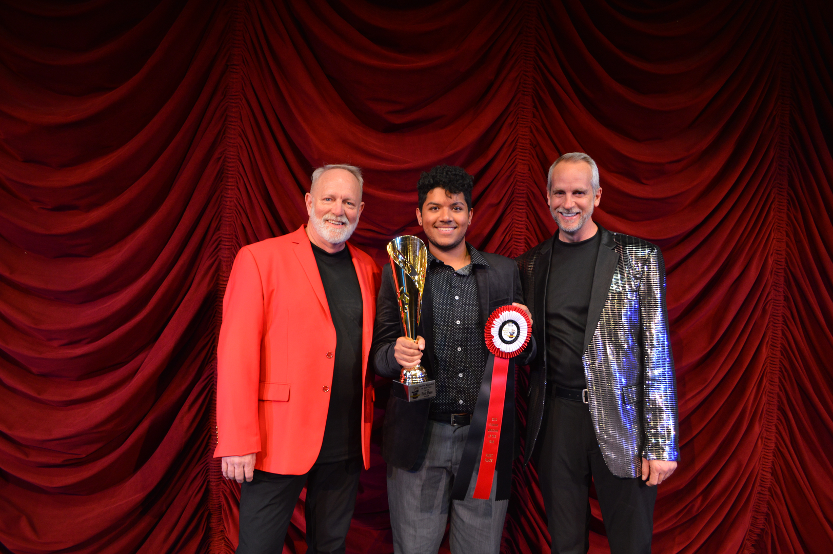 Three men standing in front of a red curtain.