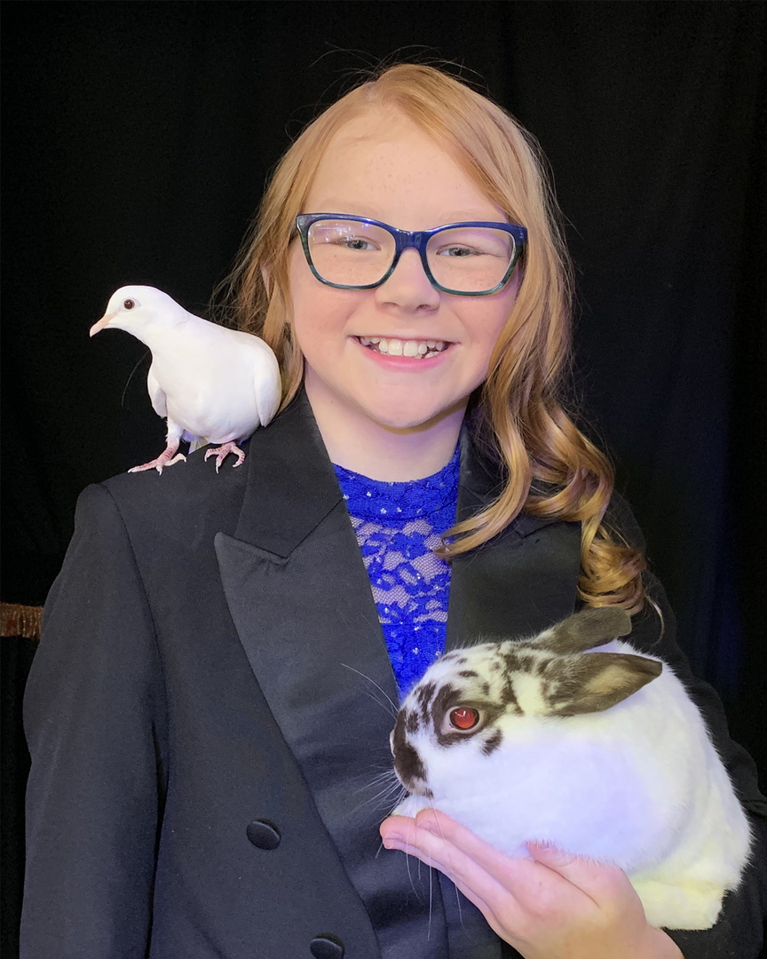A girl in glasses holding a pigeon and a dove.